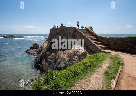 Galle, Sri Lanka - November 21, 2019: Touristen den Blick auf den Indischen Ozean genießen Sie von der Mauern von Galle Fort Ruinen Stockfoto