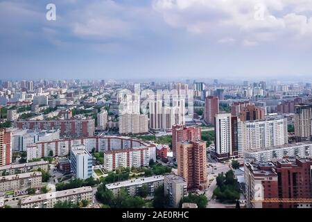 Luftaufnahme der Landschaft in einer grossen Stadt mit hohen Häusern und Wolkenkratzer im Zentrum von Nowosibirsk unter einem bewölkten Himmel mit Nebel und Dunst in einer Summe Stockfoto