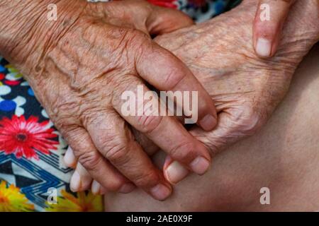 Ältere Mann und Frau halten Hände mit Liebe. Großeltern halten einander die Hände. Rentner, die in einem Pflegeheim sind langweilig. Stockfoto