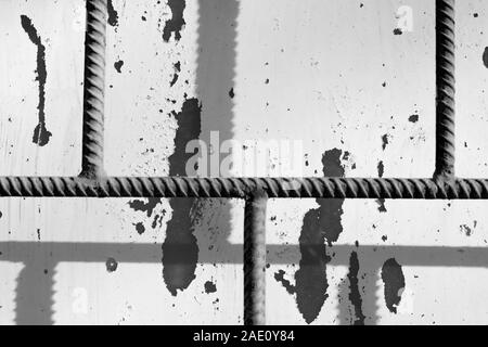 Fragment einer alte bemalte Fenster hinter einem rostigen Bars an einem sonnigen Tag. Monochrome abstrakt Hintergrund Stockfoto