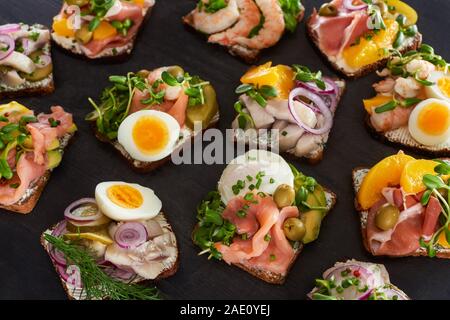 Selektiver Fokus von Roggenbrot mit vorbereiteten Dänische smorrebrod Sandwiches auf graue Oberfläche Stockfoto