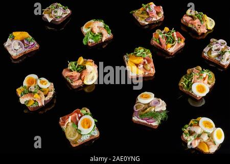 Roggenbrot mit leckeren dänischen smorrebrod Sandwiches auf Schwarz Stockfoto