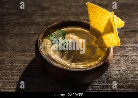 Köstliche hummus in Schüssel mit Nachos auf Holz rustikale Tabelle Stockfoto