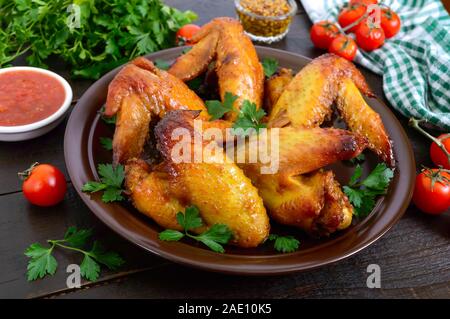 Gebackene Chicken Teriyaki Flügel in Honig Senf Sauce mit adjika und Senf auf dunklen Holztisch. Asiatische Rezept. Im rustikalen Stil Stockfoto