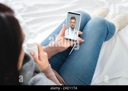 7/8-Ansicht von kranken Frau mit Pillen in On-line-Konsultation mit männlicher Arzt auf dem Smartphone Stockfoto