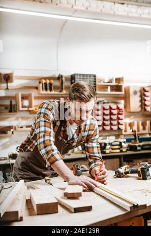 Selektiver Fokus der Bärtige woodworker messen Holzbrett Stockfoto