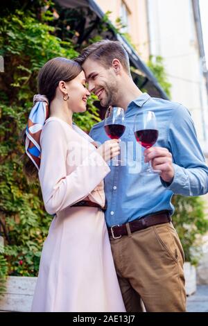 Glückliches Paar umarmen beim stehen von Angesicht zu Angesicht und halten Gläser Rotwein Stockfoto