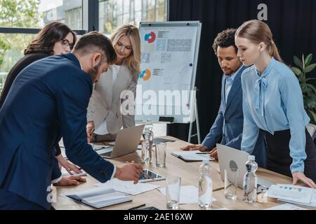 Multikulturelle Geschäftsleute auf Dokument auf Schreibtisch während der Konferenz Stockfoto