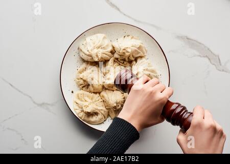 7/8-Ansicht von Frau Gewürze frische und köstliche khinkali auf Marmor tisch Stockfoto