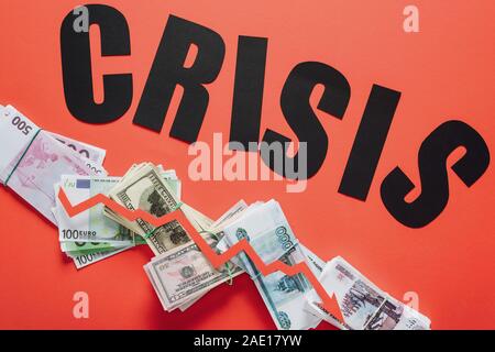 Blick von oben auf schwarzem Papier Wort Krise und Rezession Pfeil auf Dollar, Euro und Rubel Banknoten auf rotem Hintergrund Stockfoto
