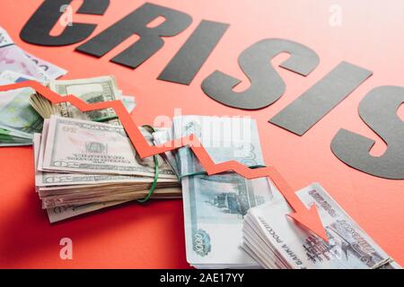 Schwarze Wort Krise und Rezession Pfeil auf Euro, Dollar und Rubel Banknoten auf rotem Hintergrund mit Beleuchtung Stockfoto