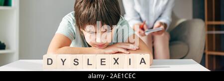 Panorama-aufnahme der traurige Kinder mit Legasthenie am Tisch sitzen mit Holzwürfeln mit Schriftzug Legasthenie Stockfoto