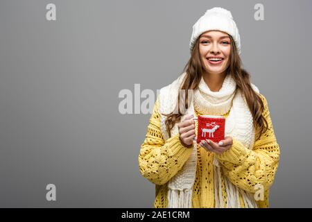 Happy girl in gelb Pullover, Schal, Hut holding Tasse Kakao auf Grau Stockfoto