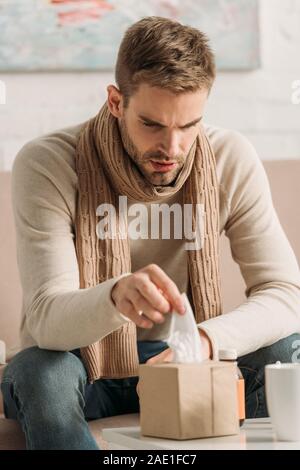 Kranken Mannes in warmer Schal mit Serviette von Pack Stockfoto