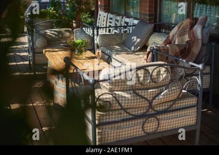 Gemütliche Terrasse mit Sofas für Rest, Glas mit Champagner auf einer hölzernen Tisch. Sonnigen Tag. Stockfoto