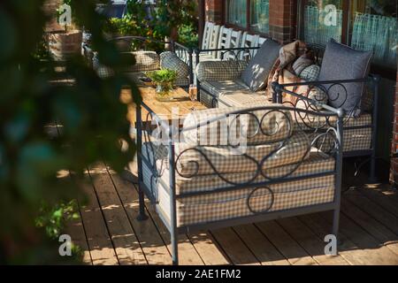 Gemütliche Terrasse mit Sofas für Rest, Glas mit Champagner auf einer hölzernen Tisch. Sonnigen Tag. Stockfoto
