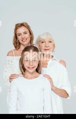 Lächelnde Mutter, Großmutter und Enkelin umarmen isoliert auf Grau Stockfoto