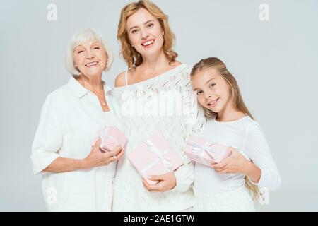 Lächelnd Enkelin, Mutter und Großmutter holding Geschenke isoliert auf Grau Stockfoto