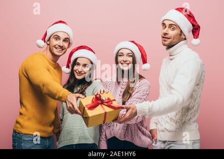 Gerne Freunde in santa Hüte geschenke weihnachten Geschenk an Sie, isoliert auf Rosa Stockfoto