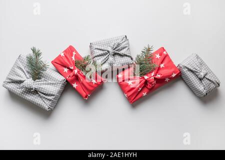 Weihnachten umweltfreundliche Geschenk in Rot und Grau Textil mit natürlichen Dekor gewickelt. Nachhaltige Geschenke. Null Abfall. Xmas eco Urlaub. Traditionelle Japanische Stockfoto