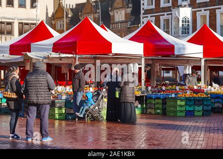 Käufer an der Open-air-gemüsehändler Marktständen verkaufen Obst auf dem Marktplatz in Northampton, England, an einem kalten, sonnigen Wintertag. Stockfoto