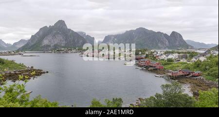 REINE, Norwegen - 14 Juli 2019: Arctic Circle fjord Stadtbild mit traditionellen Fischerboote vertäut im Hafen- und steile Hügel im Hintergrund, Schuß Stockfoto