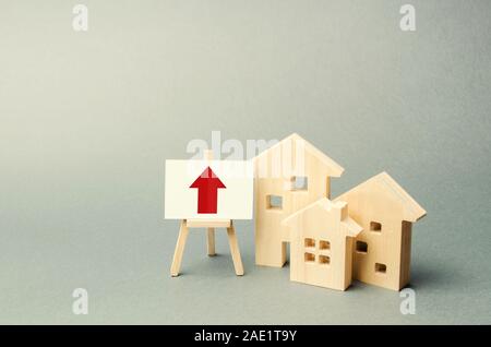 Drei Holzhäuser und ein roter Pfeil auf dem Schild. Immobilien Wert erhöhen. Hohe Konstruktion, hoher Liquidität. Angebot und Nachfrage. Steigende