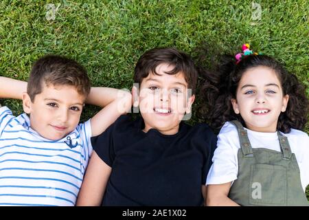 Drei glückliche Freunde im Gras liegend Stockfoto