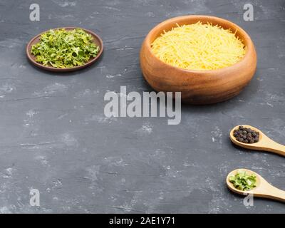 Kleine Pasta in Houten, trockene grüne Gewürze, Pfeffer Schwarz auf schwarzem konkreten Hintergrund. Gesunde Ernährung Konzept Stockfoto