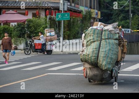 Chengdu, China - Juli 2019: Person, die schwere Last auf den Straßen in der Stadt Chengdu, Provinz Sichuan im Sommer Stockfoto