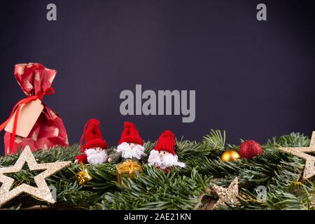 Weihnachtsdekoration (Zwerge, Gegenwart, Sterne, Kugeln) und fir Zweige vor einem schwarzen Hintergrund Stockfoto
