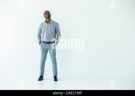 Nachdenklicher Mann stehend vor weißem Hintergrund Stockfoto