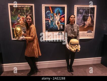 London UK Freitag, 06. Dezember 2019 zwei Galerie Assistenten, mit denen die Rückkehr der Jedi Ritter Werbe-C-3PO Helm (est. £ 15.000 - 25.000). Auch auf der High End ist ein glänzendes Gold fördernden C-3PO Kopf aus Die Rückkehr der Jedi-Ritter (1983) Bei £ 15.000 geschätzt - 25.000 (19.400 - 32.300 $) und der Prototyp eines imperialen Stormtrooper Helm (1976) von Star Wars: Episode IV - Eine neue Hoffnung (est. £ 30.000 - 60.000). Am bemerkenswertesten Los unter den 100 Lose ist ein Prototyp der legendären Imperial Stormtrooper Helm aus Star Wars: Episode IV - Eine neue Hoffnung (1977), schätzungsweise zwischen £ 30.000 - 60.000 (38.800 - 77,60 $ Stockfoto