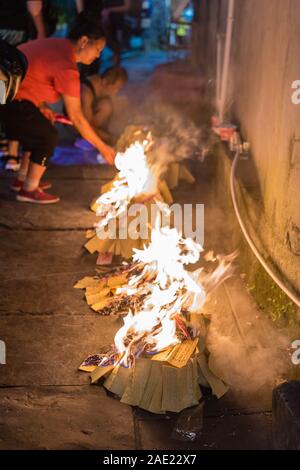 Feng Huang, China - August 2019: Menschen brennendes Papier auf Straßen und Gehwegen in ein religiöses Fest Zeremonie Bezug auf Vorfahren und spir zu zahlen Stockfoto