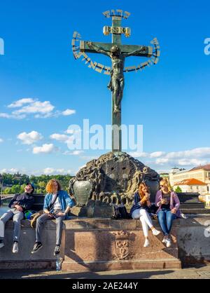 Touristen unter Skulptur Kruzifix und Golgatha sitzen mit hebräischen Text höhnische mittelalterliche jüdische Bürger der Karlsbrücke in Prag in der Tschechischen Republik. Stockfoto