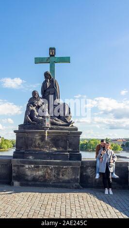 Touristen durch Replik Statue der Beweinung Christi Statue der Pietà auf der Karlsbrücke in Prag in der Tschechischen Republik. Stockfoto