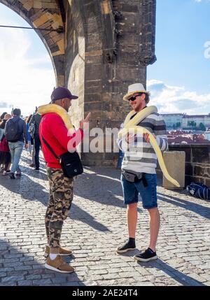 Charles Brücke zwei männliche wirbt mit python Schlangen für Touristen Fotos mit, in Prag in der Tschechischen Republik Rechnung zu tragen. Stockfoto