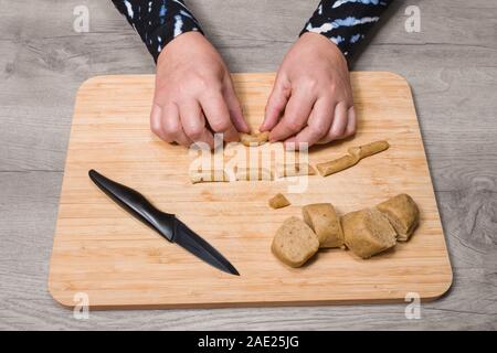 Backen süsse Vanille Crescent rollen. Weibliche Hände. Gestaltung von geschnittenen rohen Teig auf Holz Schneidebrett. Die traditionelle tschechische Weihnachten oder eine Hochzeit Cookies. Stockfoto