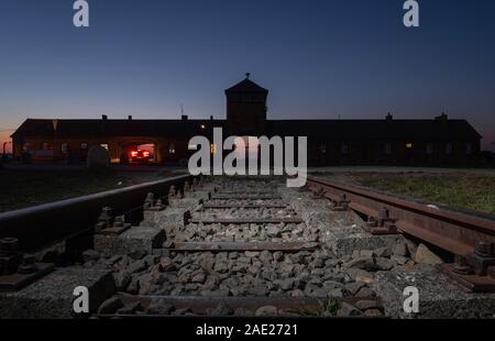 Oswiecim, Polen. 05 Dez, 2019. Blick von der Schiene auf das Eingangsportal der ehemaligen Konzentrationslager Auschwitz-Birkenau. Bundeskanzlerin Merkel (CDU) wird die Gedenkstätte im ehemaligen deutschen Konzentrationslager für den ersten Besuch am 06.12.2019. Es ist somit die Annahme einer Einladung der Stiftung Auschwitz-Birkenau anlässlich seines 10-jährigen Bestehens. (Schießen mit lange Belichtung) Credit: Robert Michael/dpa-Zentralbild/dpa/Alamy leben Nachrichten Stockfoto