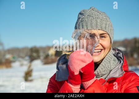 Verspielte Frau mit einem Stück Eis in den Händen auf den Winter. Stockfoto