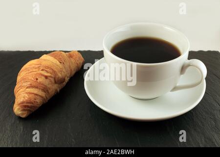 Studio geschossen von Croissant und Kaffee auf schiefer Board Stockfoto