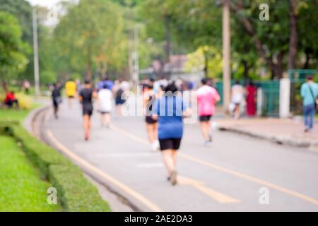 Ansicht von hinten und verschwommenes Bild von Menschen, die beim Joggen in den öffentlichen Park am Abend nach der Arbeit. Stockfoto