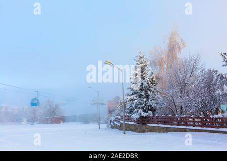 Bansko, Bulgarien winter Resort neblig Schnee Panorama mit Skipiste, Gondelbahn Kabinen, Holzzaun Stockfoto