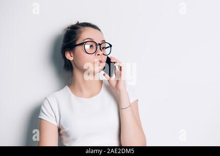 Junge schöne Frau am Telefon sprechen im Büro mit hellgrauem Hintergrund mit Kopie Raum Stockfoto