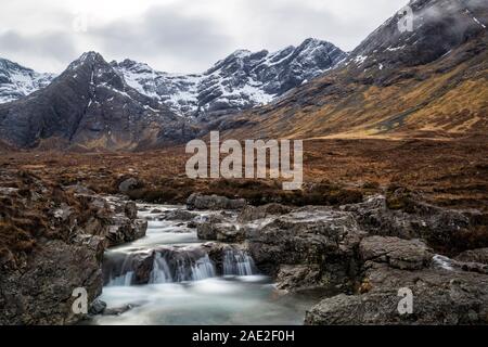 Fairy Pools mit niedrigen Wolken über die Black Cuillin Mountains mit Wasserfällen am Fluss Spröde, Isle of Skye, Schottland, UK im März - lange Belichtung Stockfoto