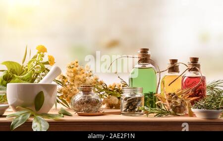 Zusammensetzung der natürlichen alternative Medizin mit Kapseln, Wesen und Pflanzen auf hölzernen Tisch in rustikale Küche. Vorderansicht. Horizontale Komposition. Stockfoto