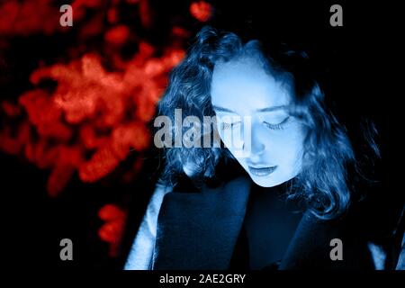 Portrait von einer geheimnisvollen Frau in Blau Nacht beleuchtung mit Red Coral Hintergrund Stockfoto