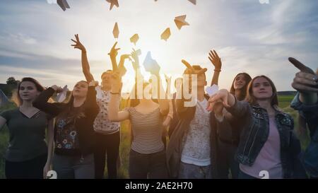 Gerne Freunde starten Papierflugzeuge bei Sonnenuntergang. Stockfoto