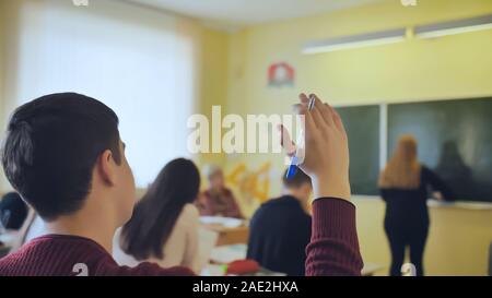 High School Student wirft seine Hand während der Lektion. Stockfoto