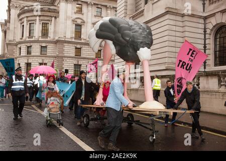 London, UK, 6. Dezember 2019: Aussterben Rebellion Demonstranten durch Westminster heute vorgeführt, mit einem 4 Meter hohen Strauß mit ihm den Kopf in den Sand. Als Symbol für die Haltung der großen politischen Parteien für die Klimakrise, der Strauß wurde durch ein Flash Mob, die "tanzte Wo ist Dein Kopf an' und 'Staying Alive' außerhalb der Zentrale der Partei der Konservativen, Liberaldemokraten und Labour Party begleitet. Anna Watson/Alamy leben Nachrichten Stockfoto